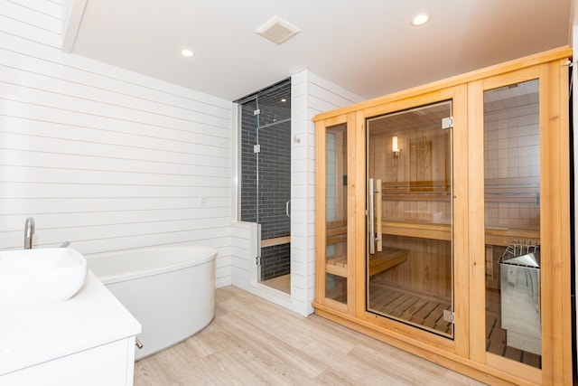 bathroom with hardwood / wood-style floors, vanity, and shower with separate bathtub