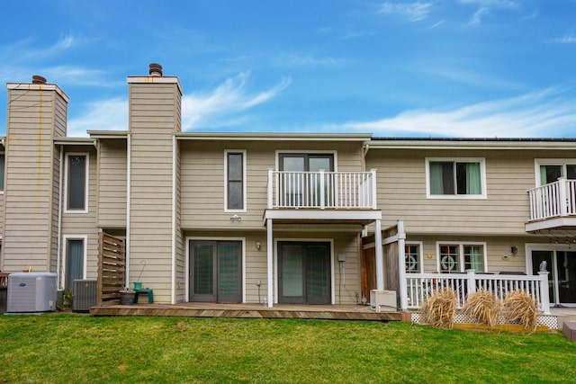 rear view of house with a balcony, a yard, and cooling unit