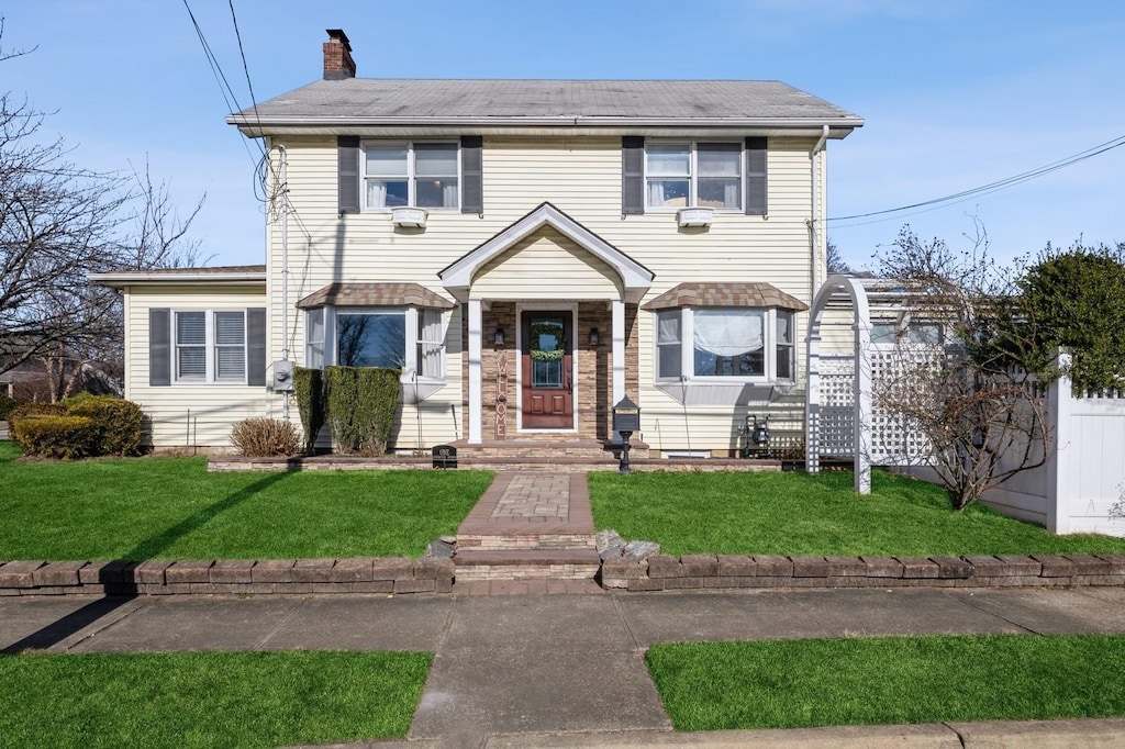 colonial-style house featuring a front lawn