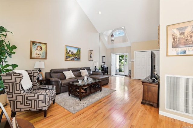 living room with light hardwood / wood-style flooring and high vaulted ceiling