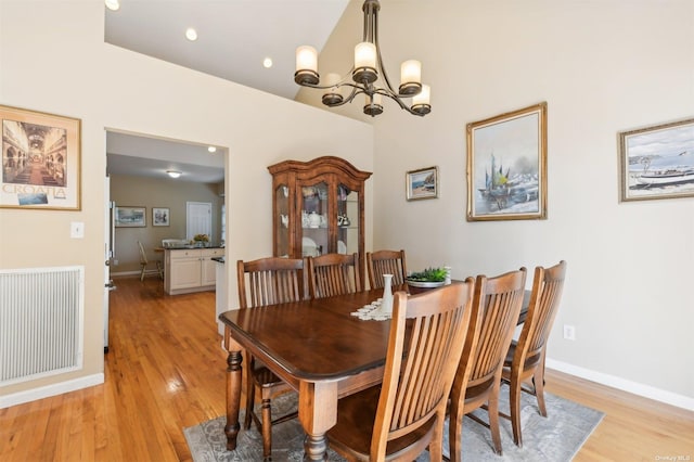 dining room featuring a chandelier, a high ceiling, and light hardwood / wood-style floors