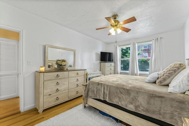 bedroom featuring a textured ceiling, light hardwood / wood-style floors, and ceiling fan