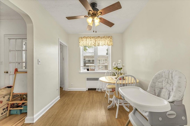 dining area with ceiling fan, light wood-type flooring, a textured ceiling, and radiator