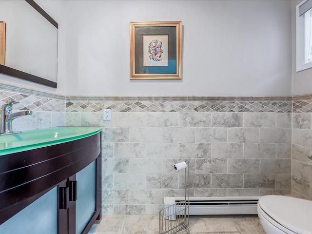 bathroom with toilet, a baseboard heating unit, tile walls, tile patterned floors, and vanity