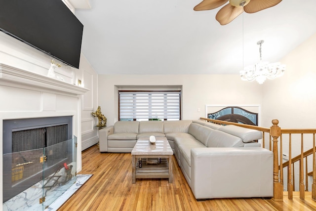 living room featuring lofted ceiling, light hardwood / wood-style flooring, and ceiling fan with notable chandelier