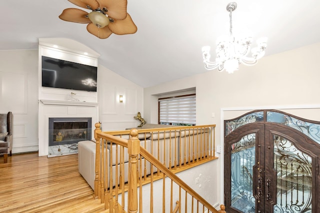 stairs with vaulted ceiling, wood-type flooring, and ceiling fan with notable chandelier