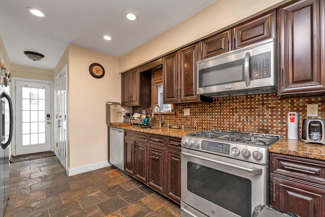 kitchen featuring dark brown cabinets, light stone counters, backsplash, and appliances with stainless steel finishes