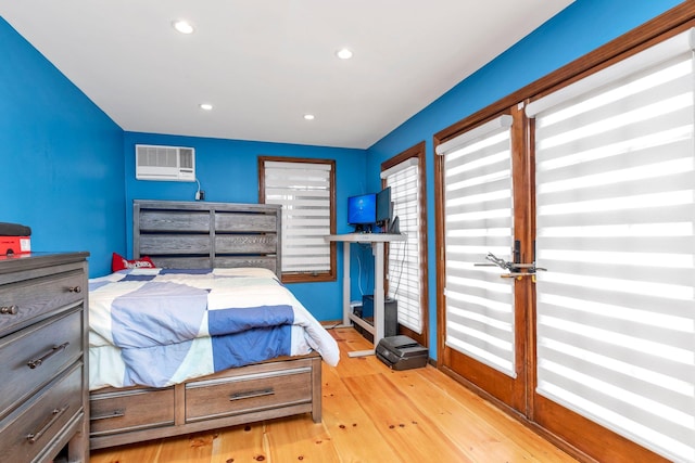 bedroom featuring light hardwood / wood-style flooring and a wall unit AC