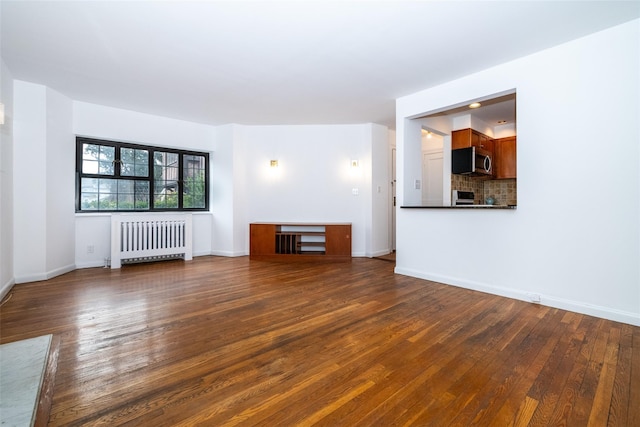 unfurnished living room featuring dark wood-type flooring, radiator, and baseboards