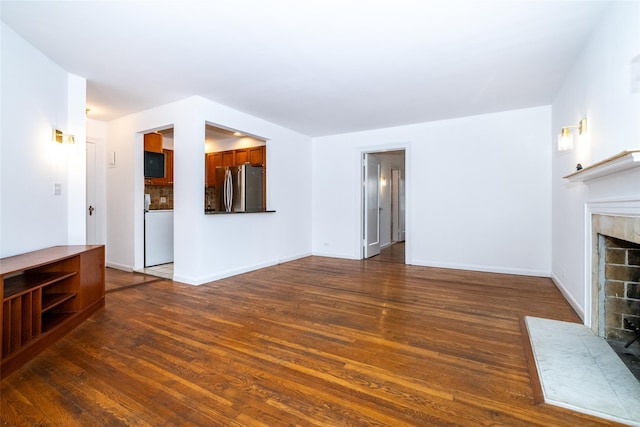 unfurnished living room with dark wood-style floors, baseboards, and a tile fireplace