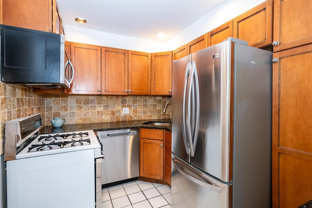 kitchen featuring appliances with stainless steel finishes, backsplash, a sink, and brown cabinets