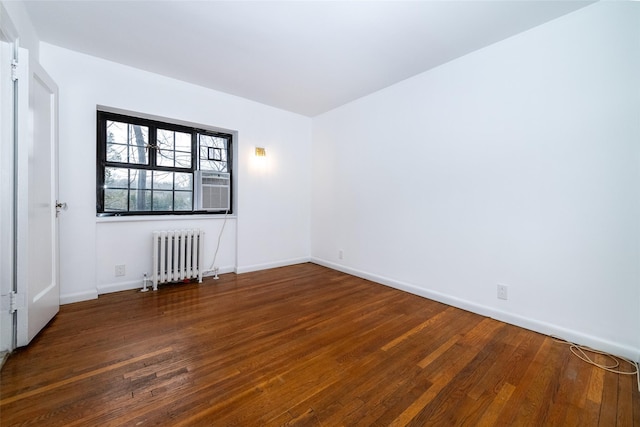 spare room with baseboards, radiator heating unit, and hardwood / wood-style flooring