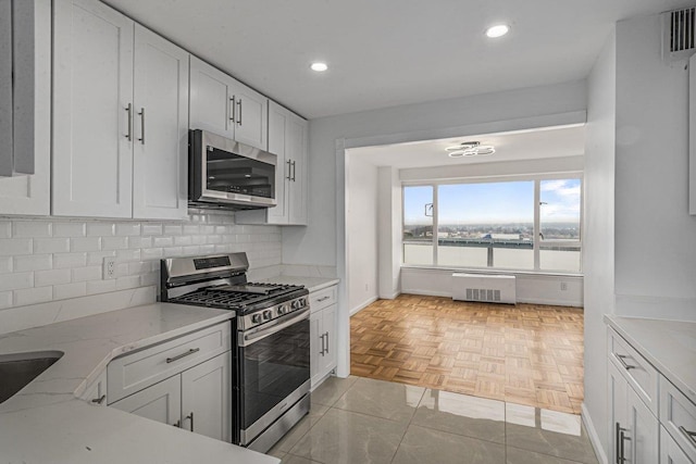 kitchen with light tile patterned flooring, stainless steel appliances, white cabinetry, and light stone counters