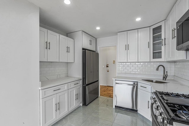 kitchen with tasteful backsplash, sink, white cabinets, and stainless steel appliances