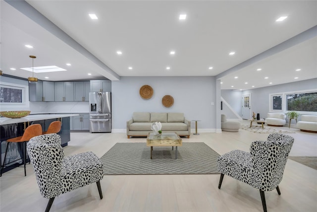 living room with a skylight and light hardwood / wood-style flooring