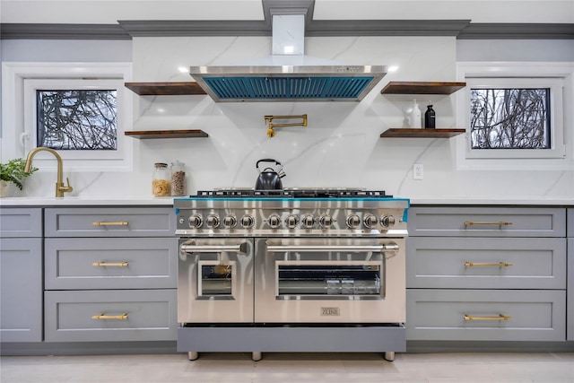 kitchen with extractor fan, range with two ovens, gray cabinets, and sink