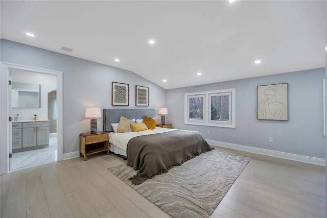 bedroom featuring light wood-type flooring, ensuite bathroom, and lofted ceiling