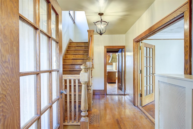 hall featuring a notable chandelier, french doors, and light wood-type flooring