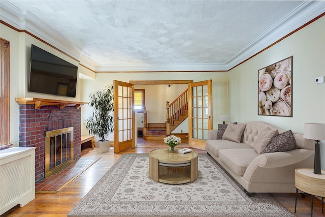 living room with hardwood / wood-style floors, ornamental molding, radiator heating unit, and french doors