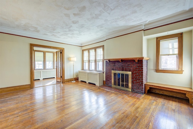 unfurnished living room featuring crown molding, hardwood / wood-style floors, a textured ceiling, and a fireplace