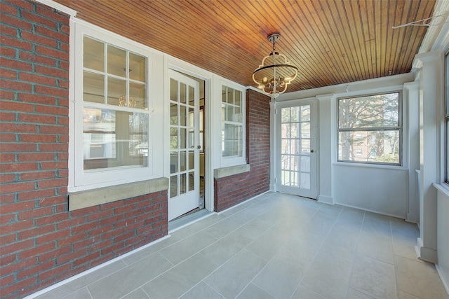 unfurnished sunroom featuring an inviting chandelier and wooden ceiling