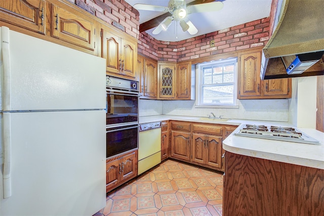 kitchen with sink, custom exhaust hood, white appliances, ceiling fan, and brick wall