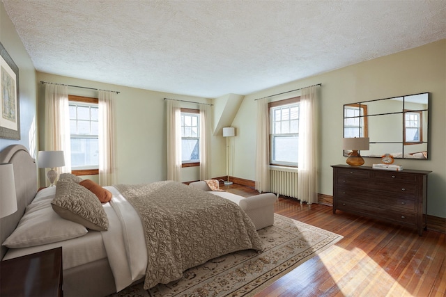 bedroom with radiator heating unit, light hardwood / wood-style floors, and a textured ceiling