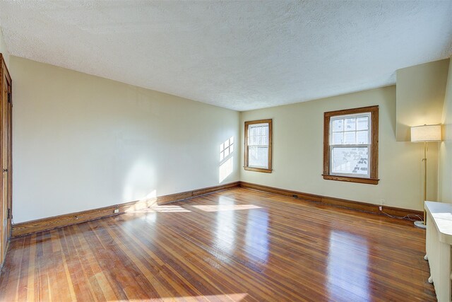 unfurnished room with wood-type flooring and a textured ceiling