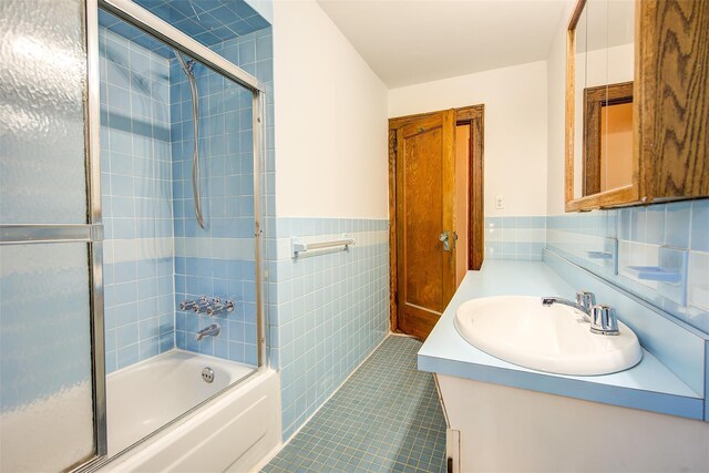 bathroom featuring tile patterned flooring, vanity, tile walls, and shower / bath combination with glass door