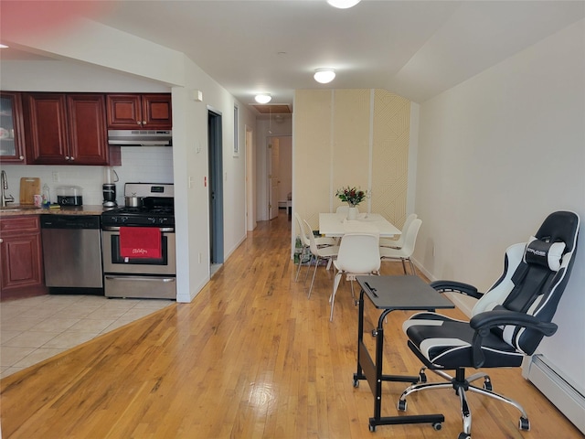 kitchen featuring sink, stainless steel appliances, a baseboard radiator, decorative backsplash, and light wood-type flooring