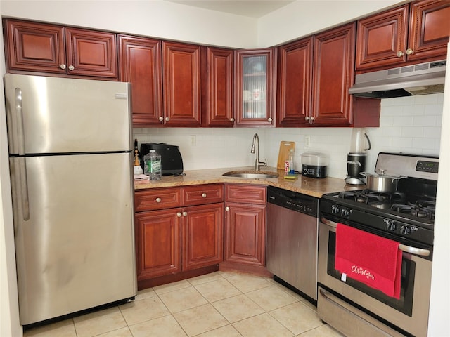 kitchen with sink, stainless steel appliances, light stone counters, decorative backsplash, and light tile patterned floors