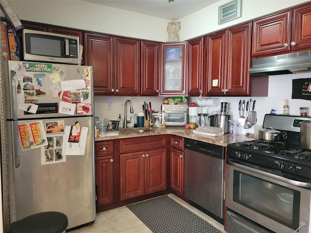 kitchen with light stone countertops, light tile patterned floors, stainless steel appliances, and sink