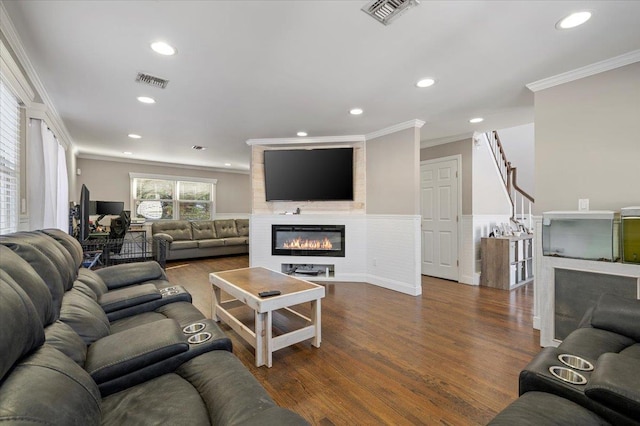 living area with dark wood-style floors, visible vents, recessed lighting, a fireplace, and crown molding