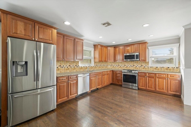 kitchen with dark wood finished floors, visible vents, stainless steel appliances, and ornamental molding