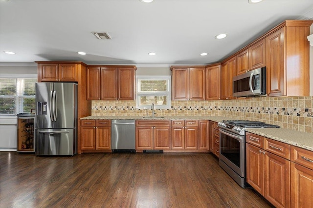 kitchen featuring visible vents, a sink, dark wood-style floors, stainless steel appliances, and light stone countertops