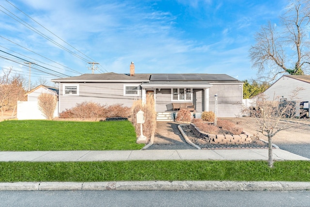 view of front facade with a porch, solar panels, and a front yard