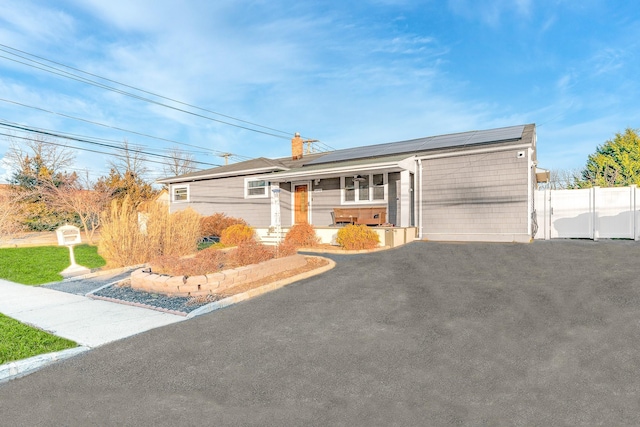 single story home with solar panels and covered porch