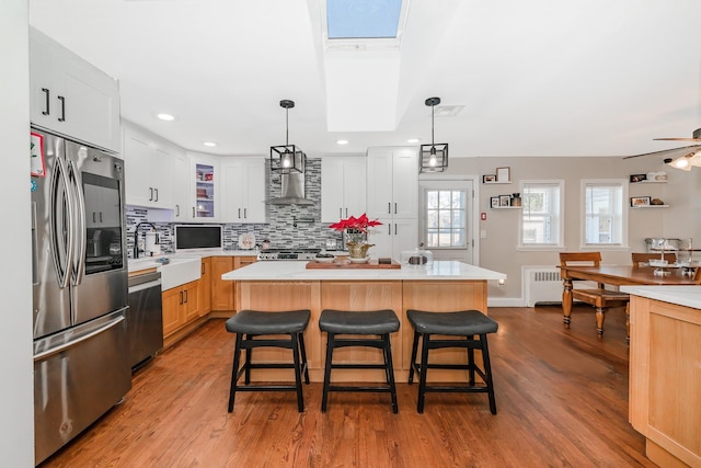 kitchen featuring stainless steel appliances, a kitchen island, white cabinets, and a skylight