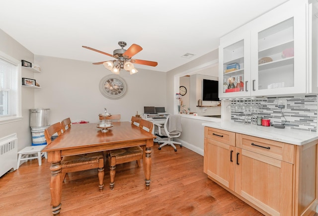 dining area featuring radiator heating unit, ceiling fan, and light hardwood / wood-style flooring