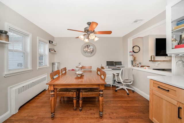 dining space featuring dark wood-type flooring, ceiling fan, and radiator