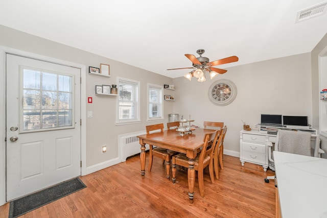 dining space with ceiling fan, light hardwood / wood-style floors, a wealth of natural light, and radiator