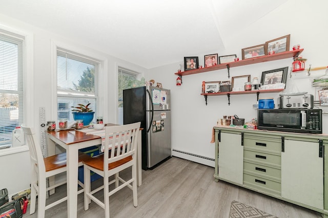 kitchen with green cabinets, a baseboard heating unit, light hardwood / wood-style floors, and stainless steel fridge