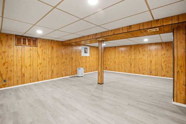 basement featuring hardwood / wood-style flooring, a paneled ceiling, and wood walls