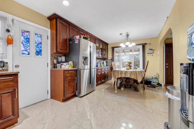 kitchen with decorative light fixtures, tasteful backsplash, stainless steel refrigerator with ice dispenser, and an inviting chandelier