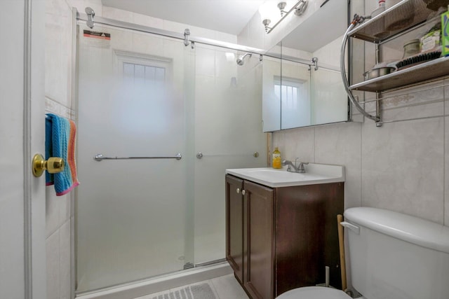 bathroom featuring tile patterned floors, an enclosed shower, toilet, vanity, and tile walls