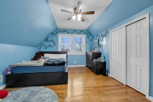 bedroom featuring a closet, light hardwood / wood-style floors, ceiling fan, and lofted ceiling