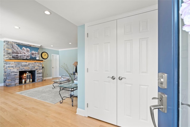 interior space with wood-type flooring, a stone fireplace, and ornamental molding