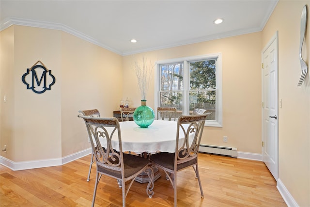 dining area with a baseboard heating unit, ornamental molding, and light hardwood / wood-style floors