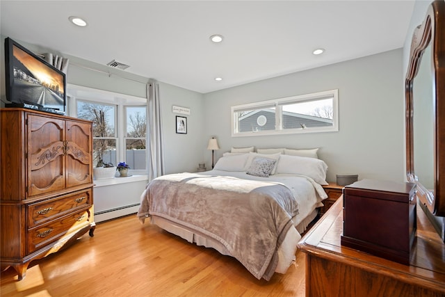 bedroom featuring a baseboard heating unit and light hardwood / wood-style flooring