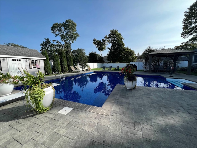 view of swimming pool with a diving board, a patio area, an outbuilding, and a gazebo